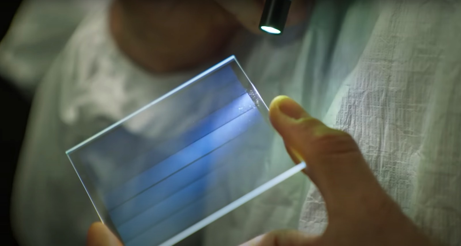 Uma pessoa inspecionando uma folha de vidro contendo dados.