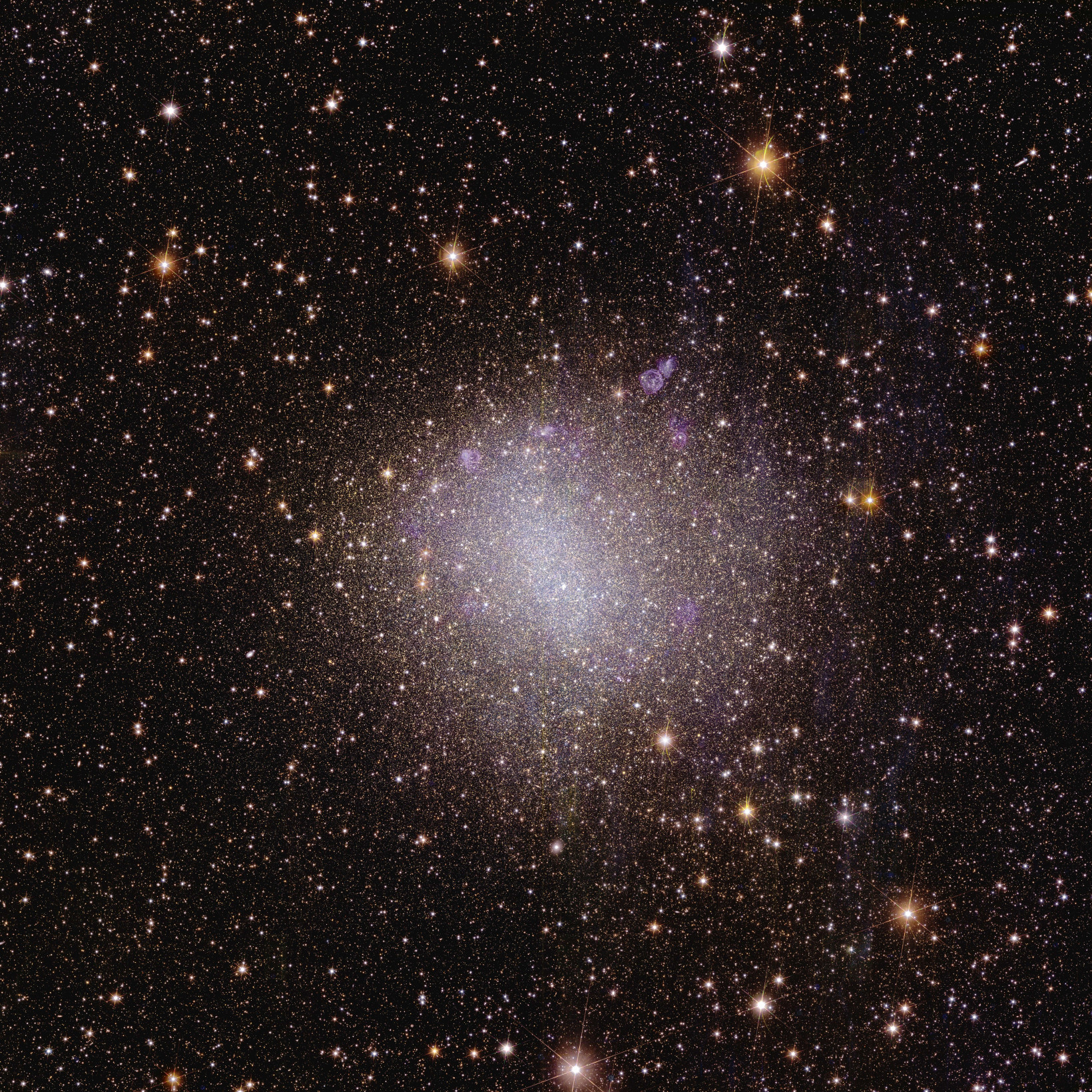 Uma imagem astronômica quadrada está salpicada de numerosas estrelas visíveis na extensão negra do espaço.  A maioria das estrelas são visíveis apenas como pontos precisos